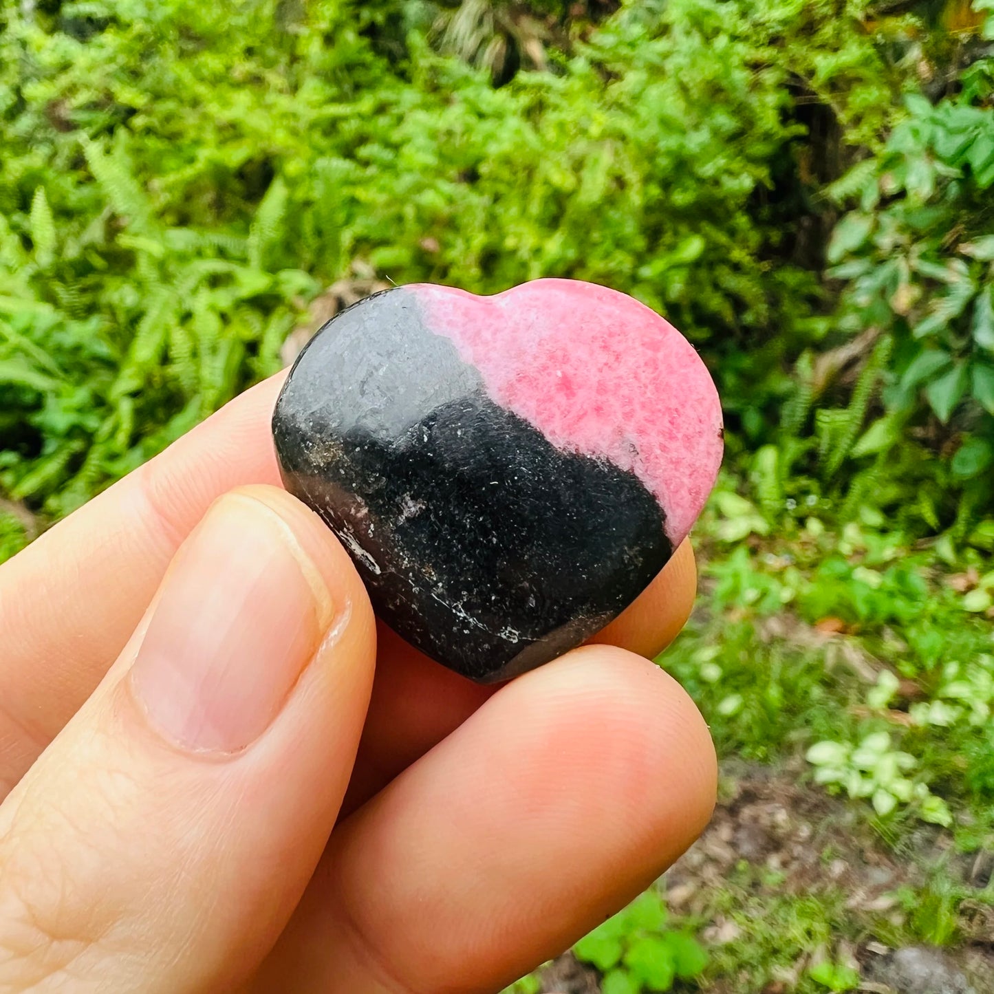 Edge-on view of Rhodonite polished heart, showing translucent edges, hand-selected from Atsimo-Andrefana, Madagascar.