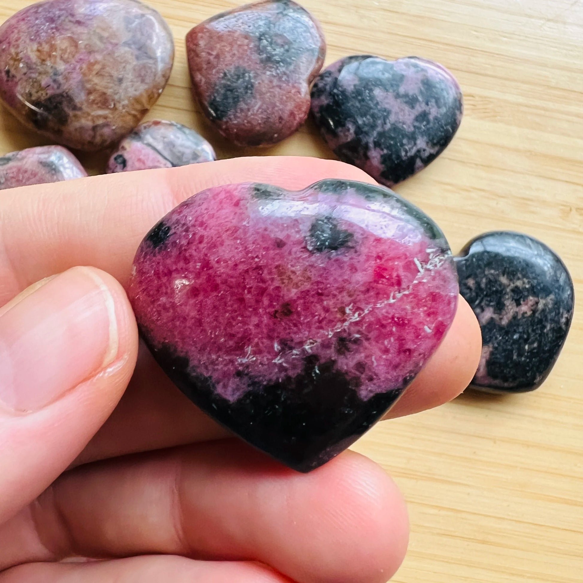 Size comparison with a single Rhodonite polished heart sourced from Madagascar.