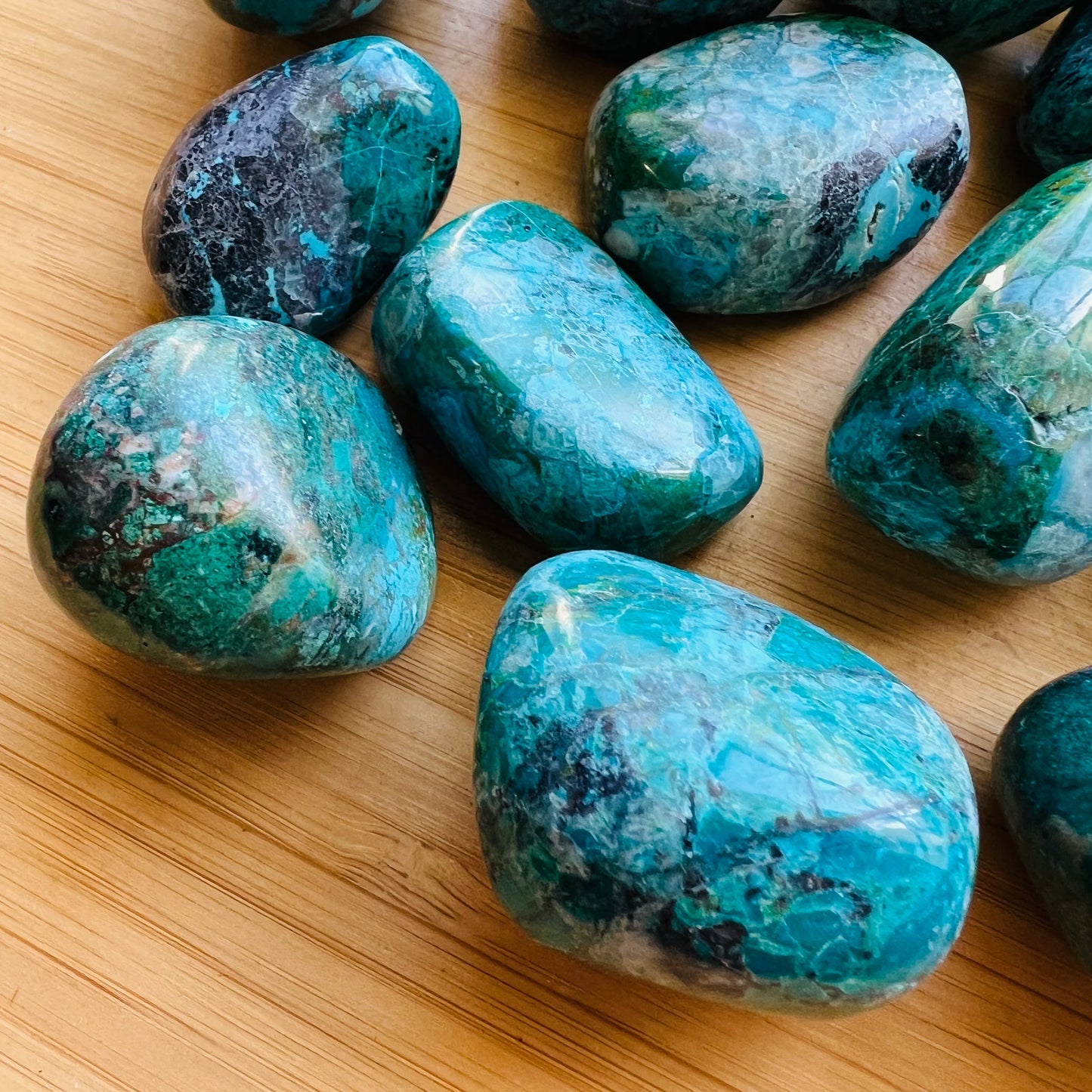 Top-down shot of Chrysocolla tumbled stone, showing earthy tone, sourced from Arequipa, Peru.