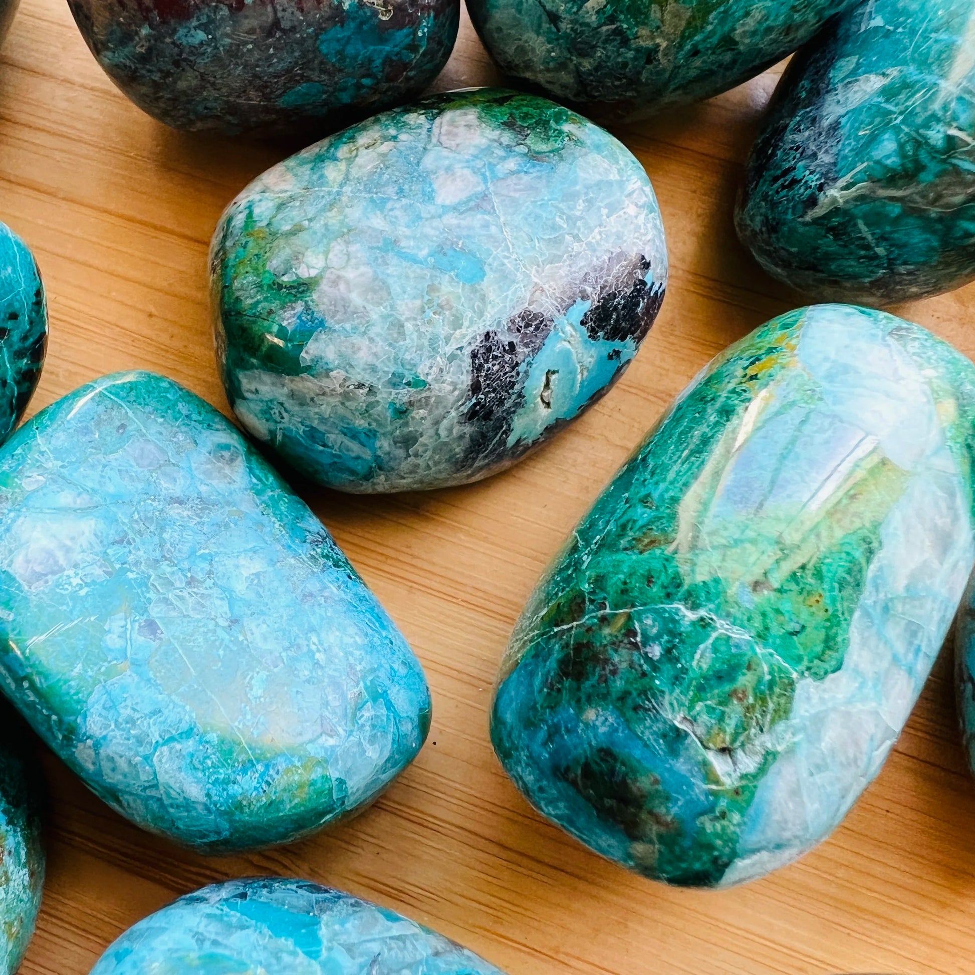 Held in hand, a single Chrysocolla tumbled stone sourced from Arequipa, Peru.