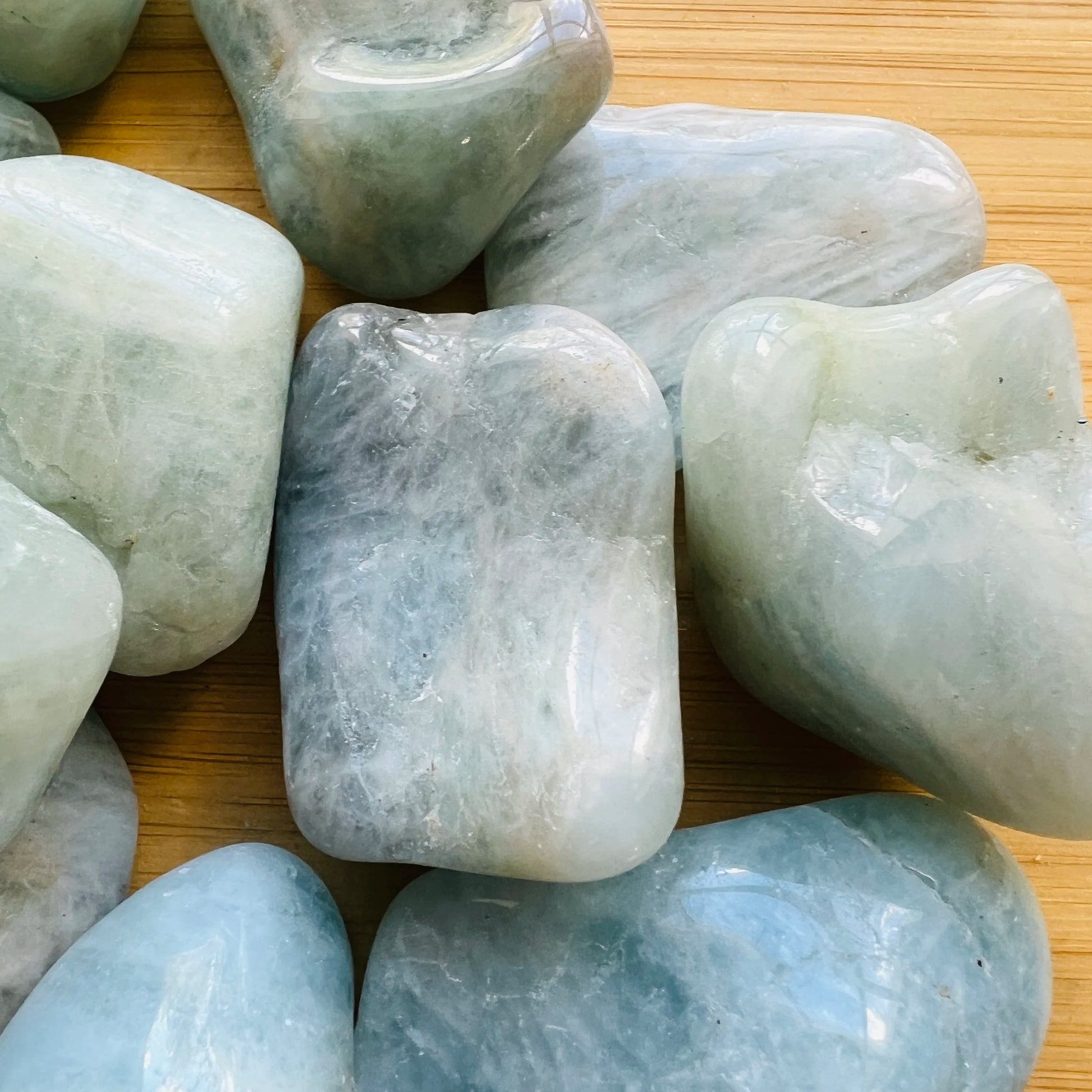 Edge view of Aquamarine tumbled stone, traditionally used for Stress Relief, showing characteristic color.