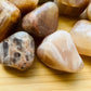 Side-on view of Grade AA Earth Moonstone tumbled stone, showing translucent edges.