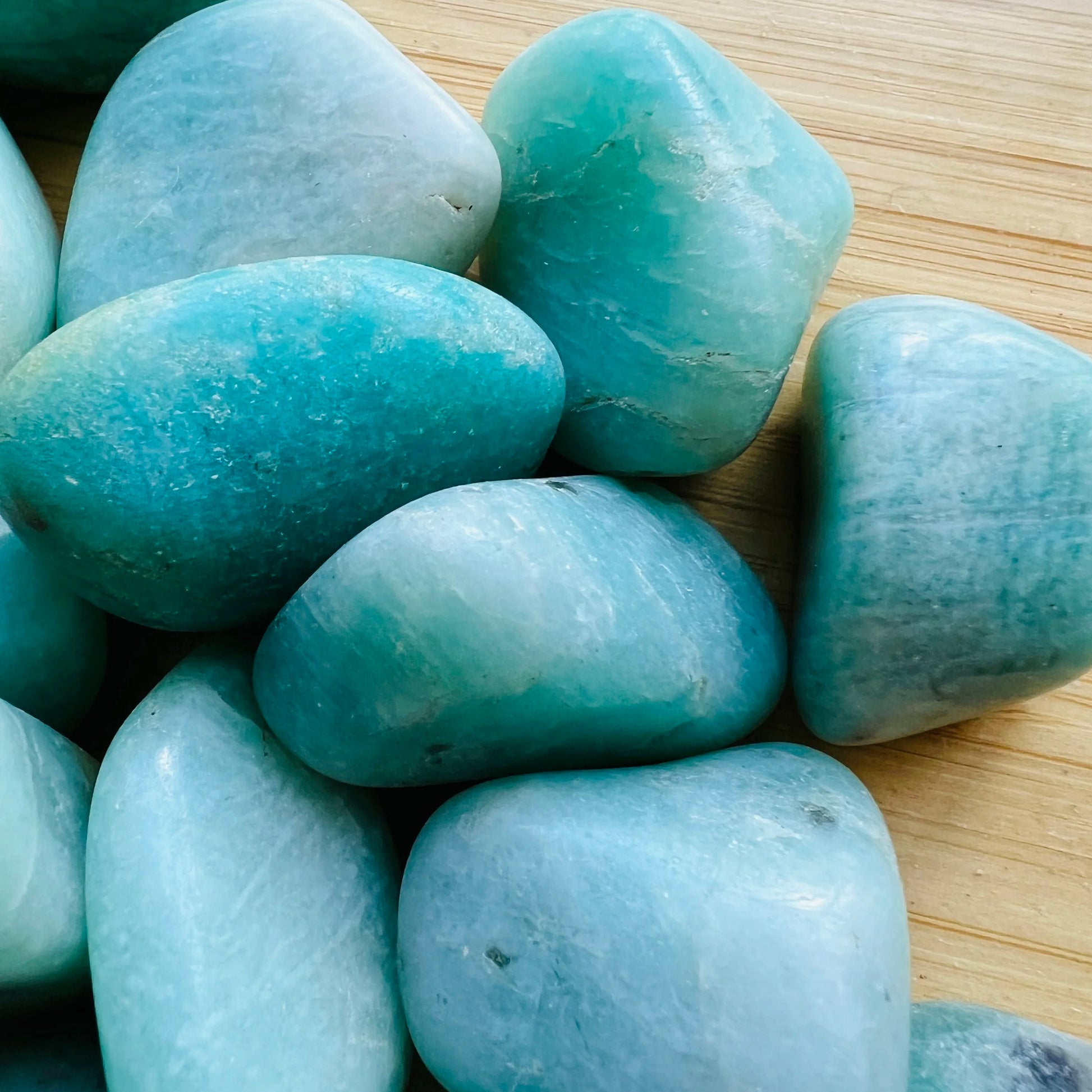 Lifestyle view of a single Amazonite tumbled stone from Brazil.