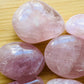 Natural light context of Rose Quartz palm stone, associated with Self Love, showing the full body of the piece.