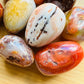 Close-up detail of Grade AA Carnelian palm stone showing natural orange, red tones and texture