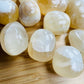 Side perspective of Honey Calcite tumbled stone, turned to for Confidence and Career, hand-selected from Ancash, Peru.