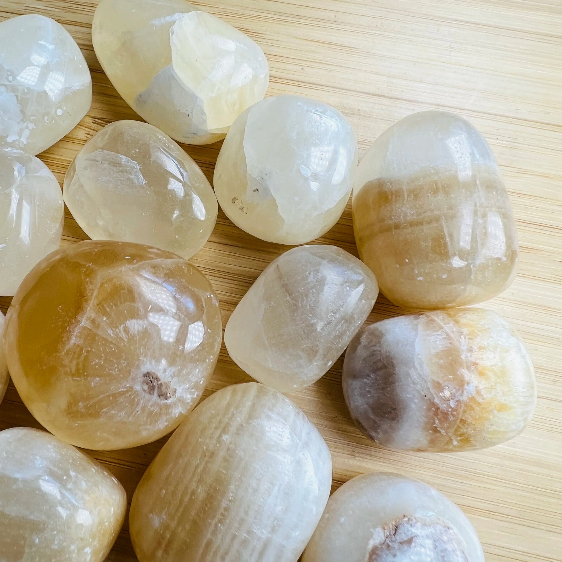 Lifestyle view of a Honey Calcite tumbled stone held against natural backdrop, from Ancash, Peru.