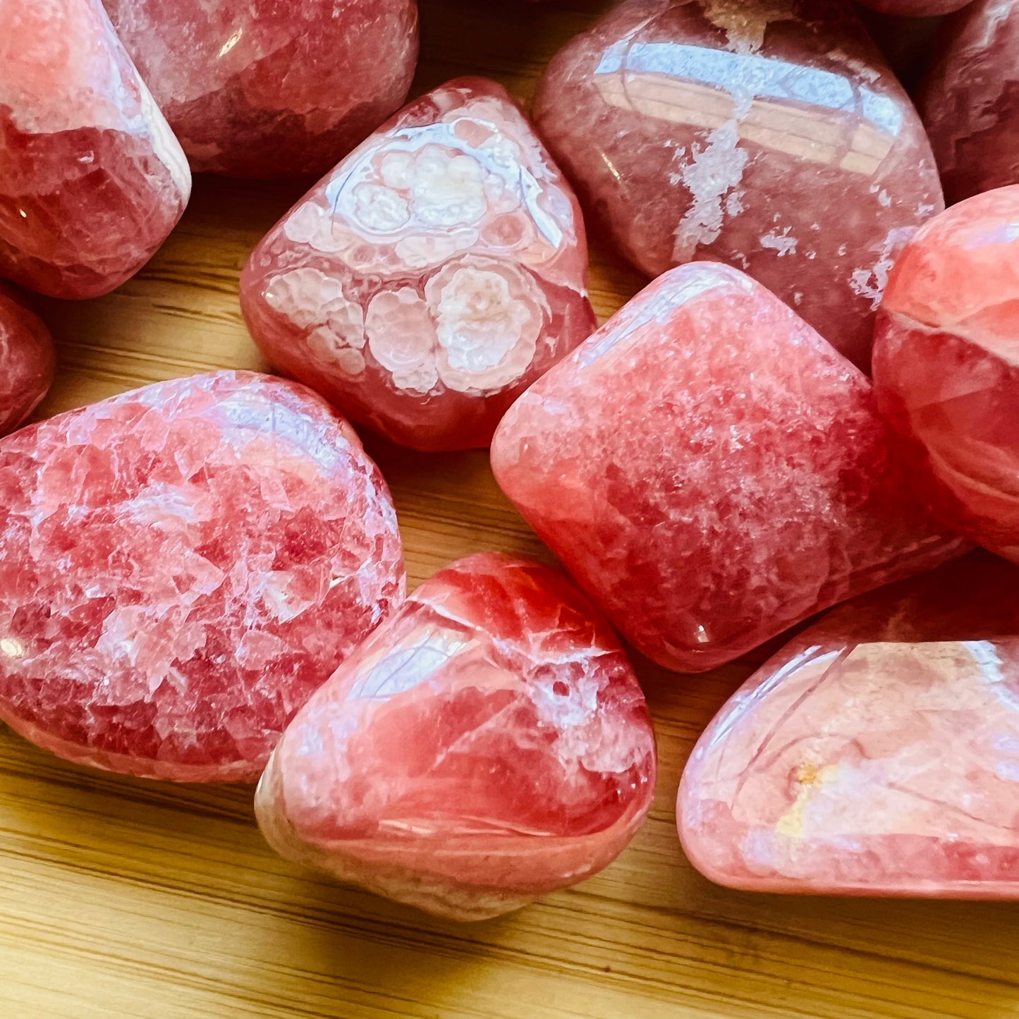 Near view of Grade AA pink Rhodochrosite tumbled stone, showing natural variation, often kept for Emotional Healing.
