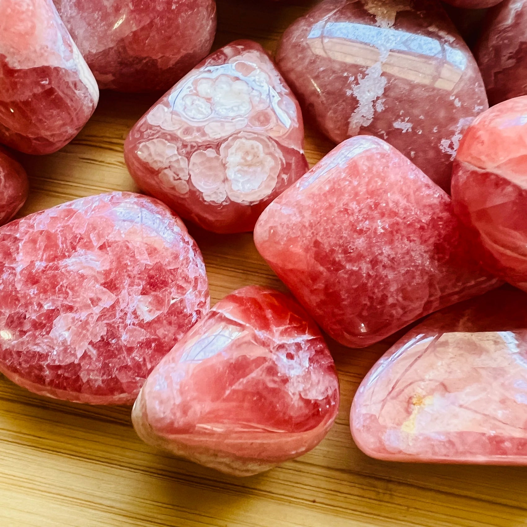Near view of Grade AA pink Rhodochrosite tumbled stone, showing natural variation, often kept for Emotional Healing.