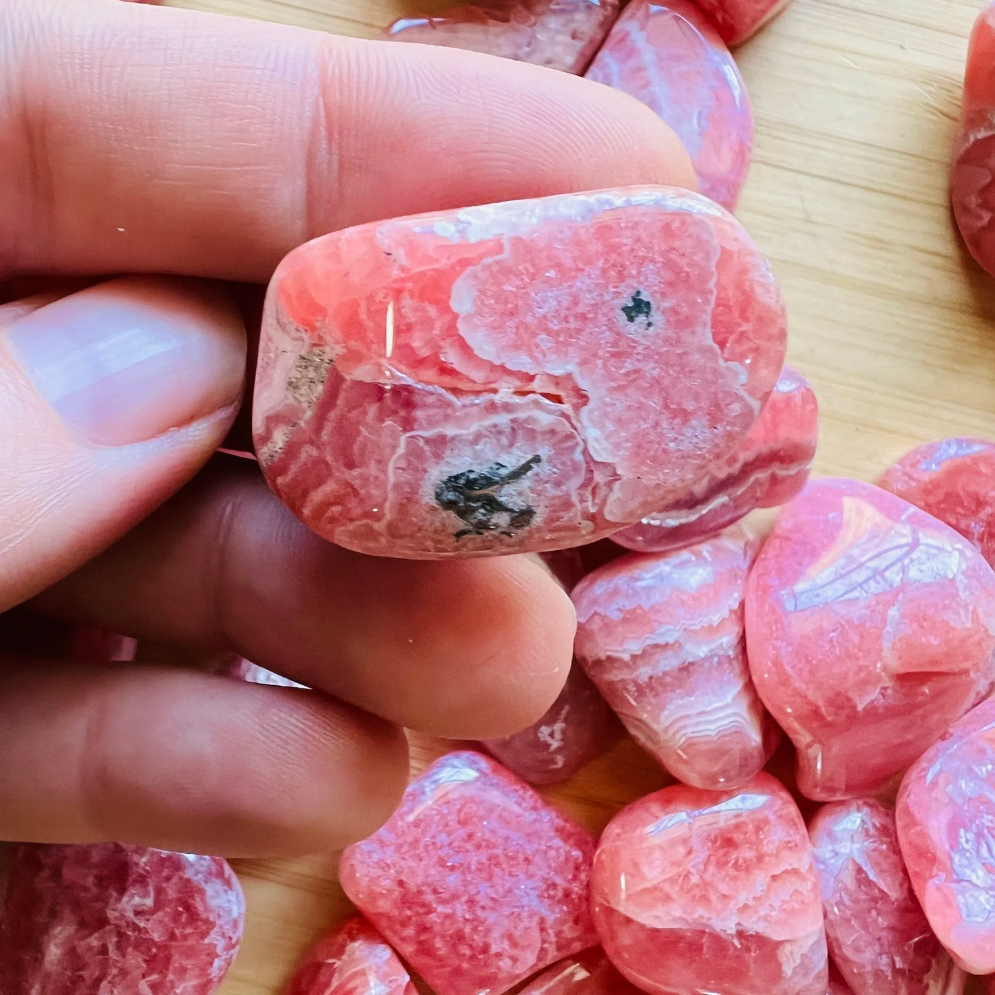 Detail shot of Grade AA Rhodochrosite tumbled stone under natural light