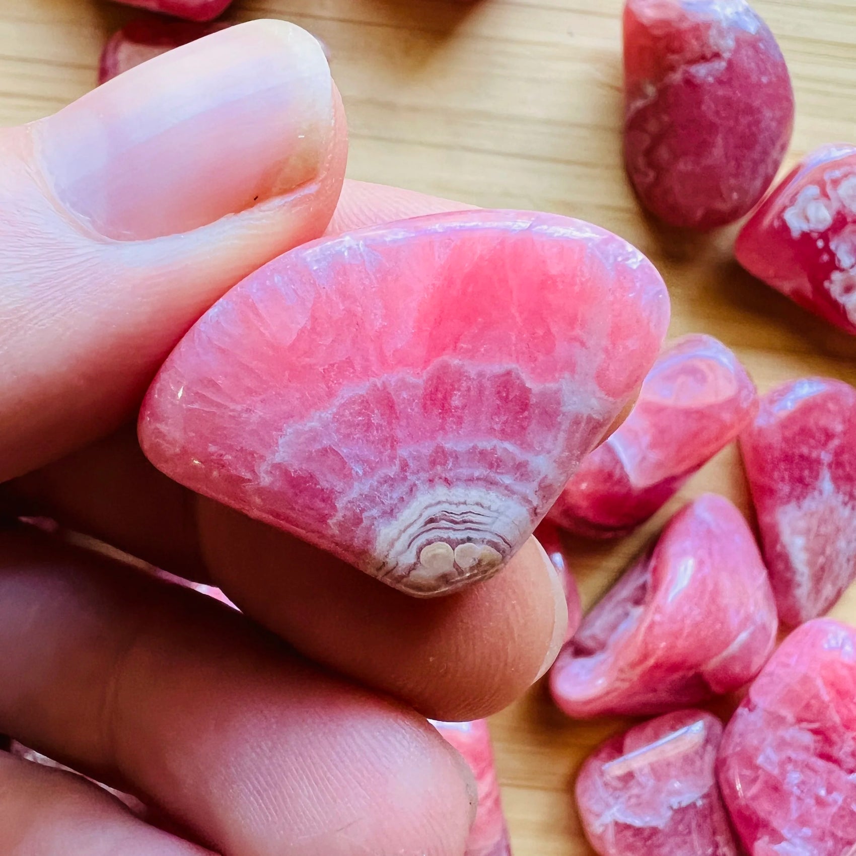 Sideways view of Grade AA Rhodochrosite tumbled stone, worked with for Emotional Healing and Love.