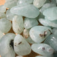 Edge-on view of Prehnite tumbled stone, showing natural sheen.