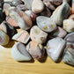 Side perspective of Pink Agate tumbled stone, showing natural texture, drawn on for Love.