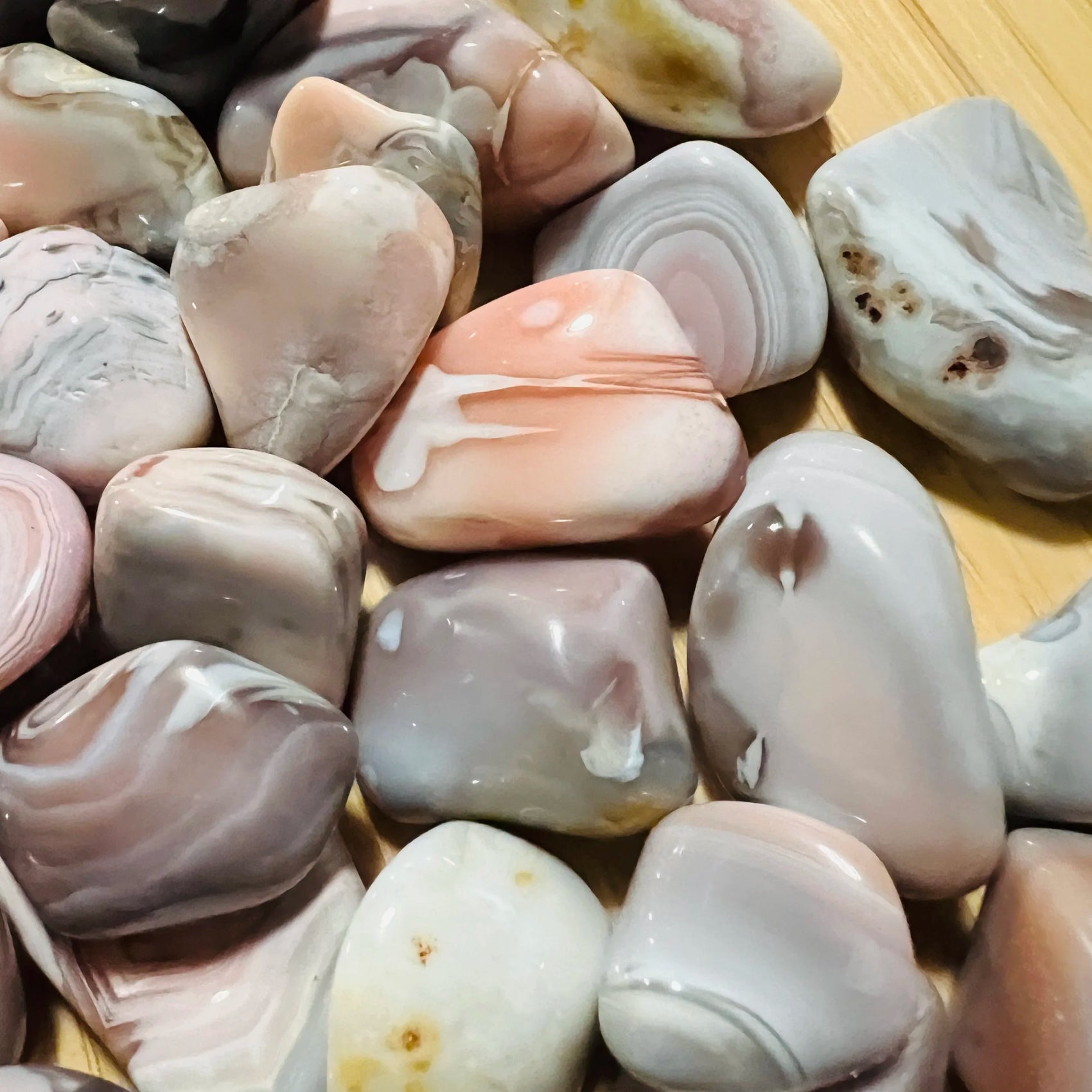 Hand-held view of a Pink Agate tumbled stone often worked with for Love and Self Love, from Botswana.