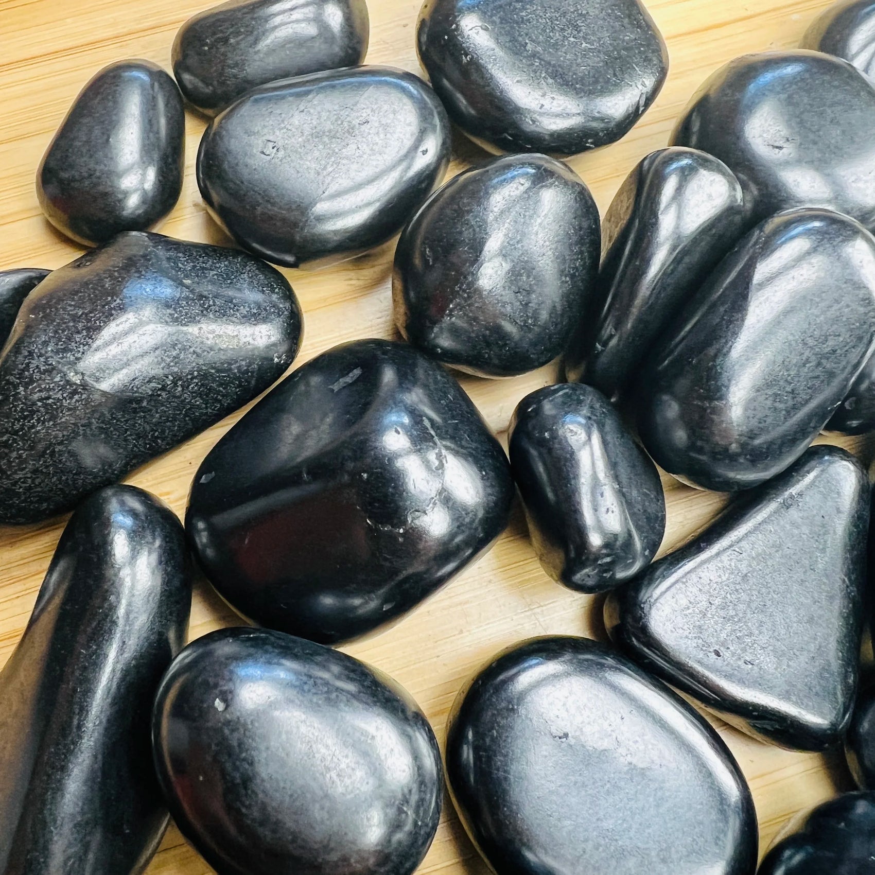 Side-on view of Shungite tumbled stone, to support Protection, showing soft luster.