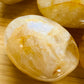 Side perspective of Golden Healer palm stone, showing natural sheen, kept close for Healing and Meditation.