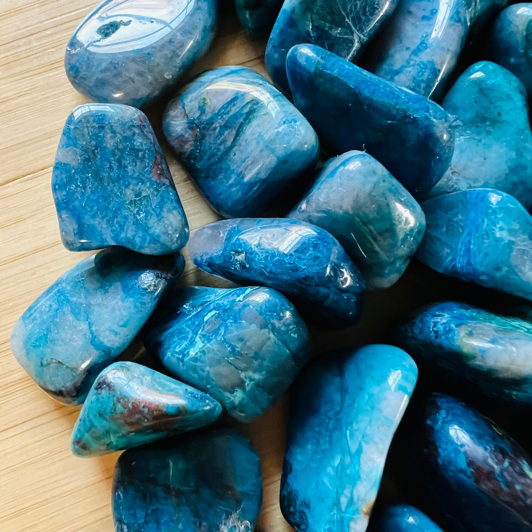 Bird's-eye view of Grade AA Chrysocolla tumbled stone, Namibia-sourced, showing natural sheen.