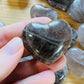 Hand-scale shot of one Smoky Quartz polished heart for scale, sourced from Madagascar.