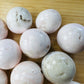 Size comparison with a Mangano Calcite tumbled stone to support Emotional Healing and Self Love, Peru-sourced.