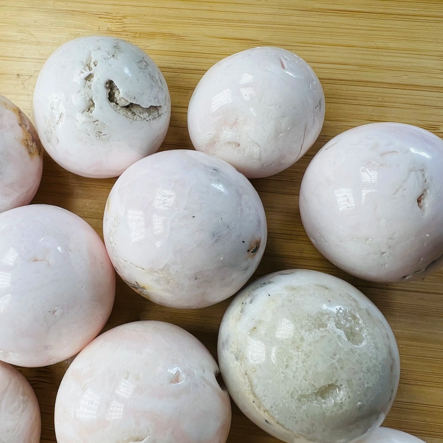 Size comparison with a Mangano Calcite tumbled stone to support Emotional Healing and Self Love, Peru-sourced.