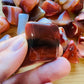 Back view of Grade AA Carnelian tumbled stone showing natural surface