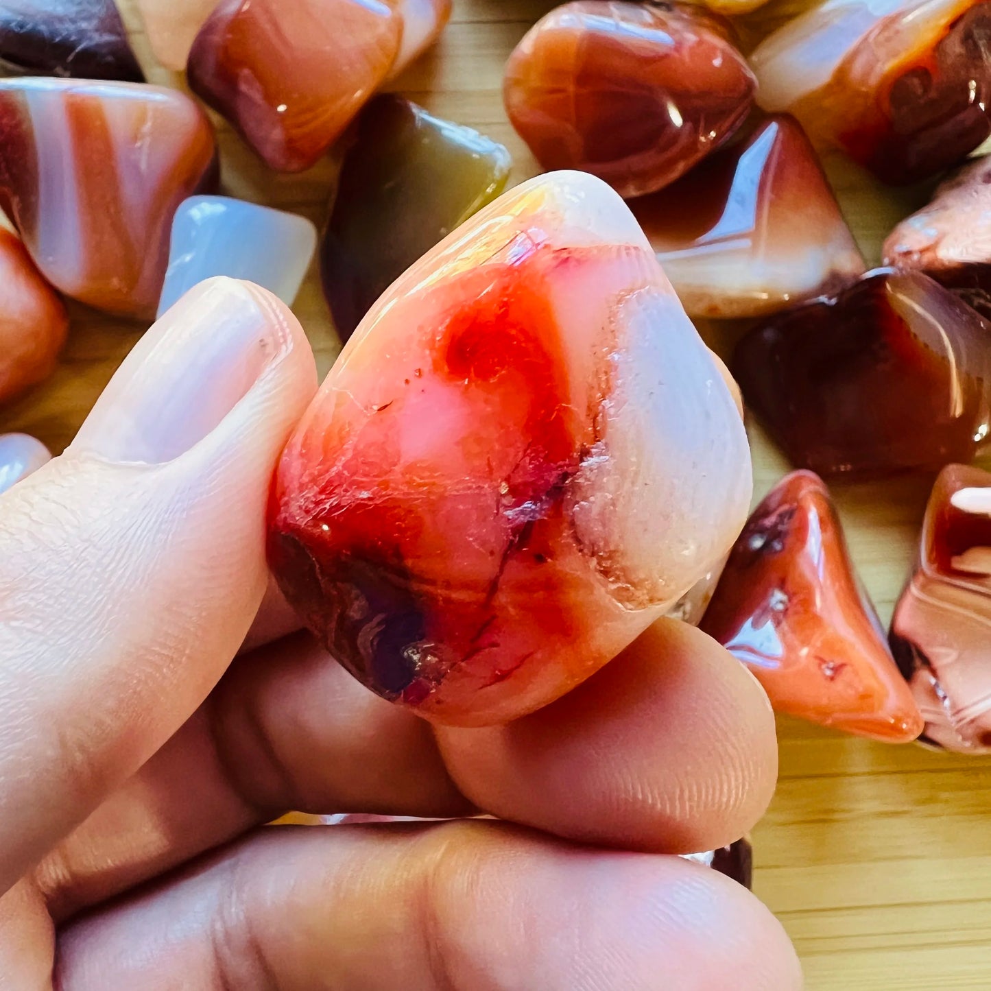 Grade aa carnelian tumbled stone held in hand for size reference
