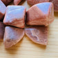 Edge view of Peach Moonstone tumbled stone, often kept for Emotional Healing and Self Love.