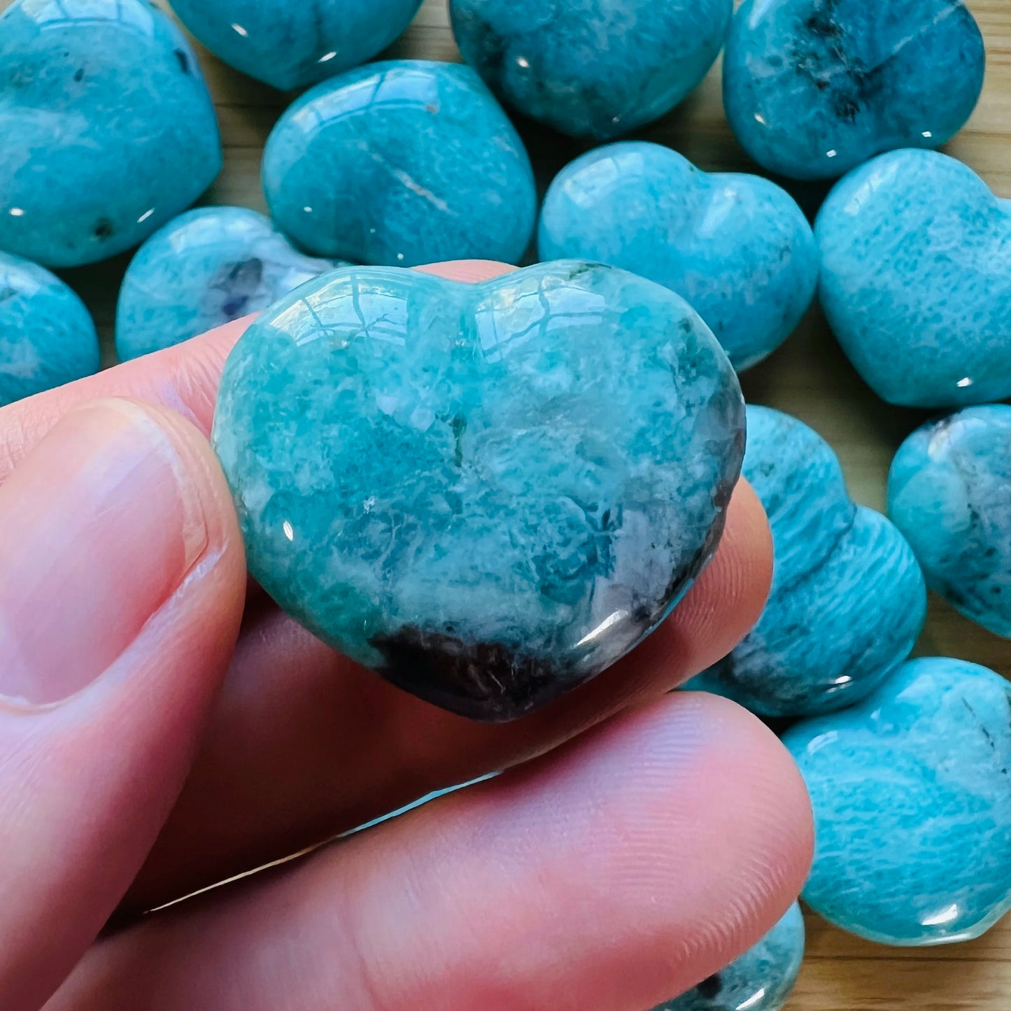 Natural light view of a Amazonite polished heart held against natural backdrop, Madagascar-sourced.