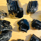 Grade aaa black tourmaline raw held in hand for size reference