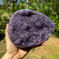 Grade aa amethyst geode held in hand for size reference