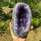 Grade aaa amethyst geode held in hand for size reference