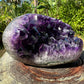 Scale reference of a Amethyst raw geode held against natural backdrop.