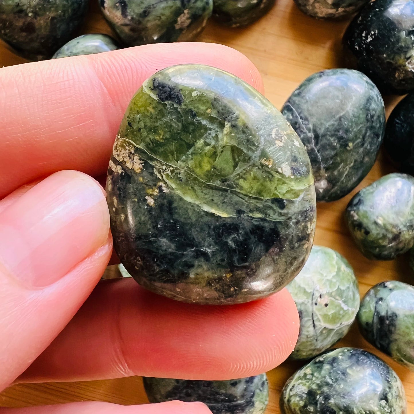 Lifestyle view of a Jade tumbled stone, sourced from Peru.