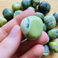 In-hand view of a Serpentine tumbled stone, sourced from Peru.