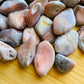 Side profile of Pink Agate tumbled stone, showing natural texture.