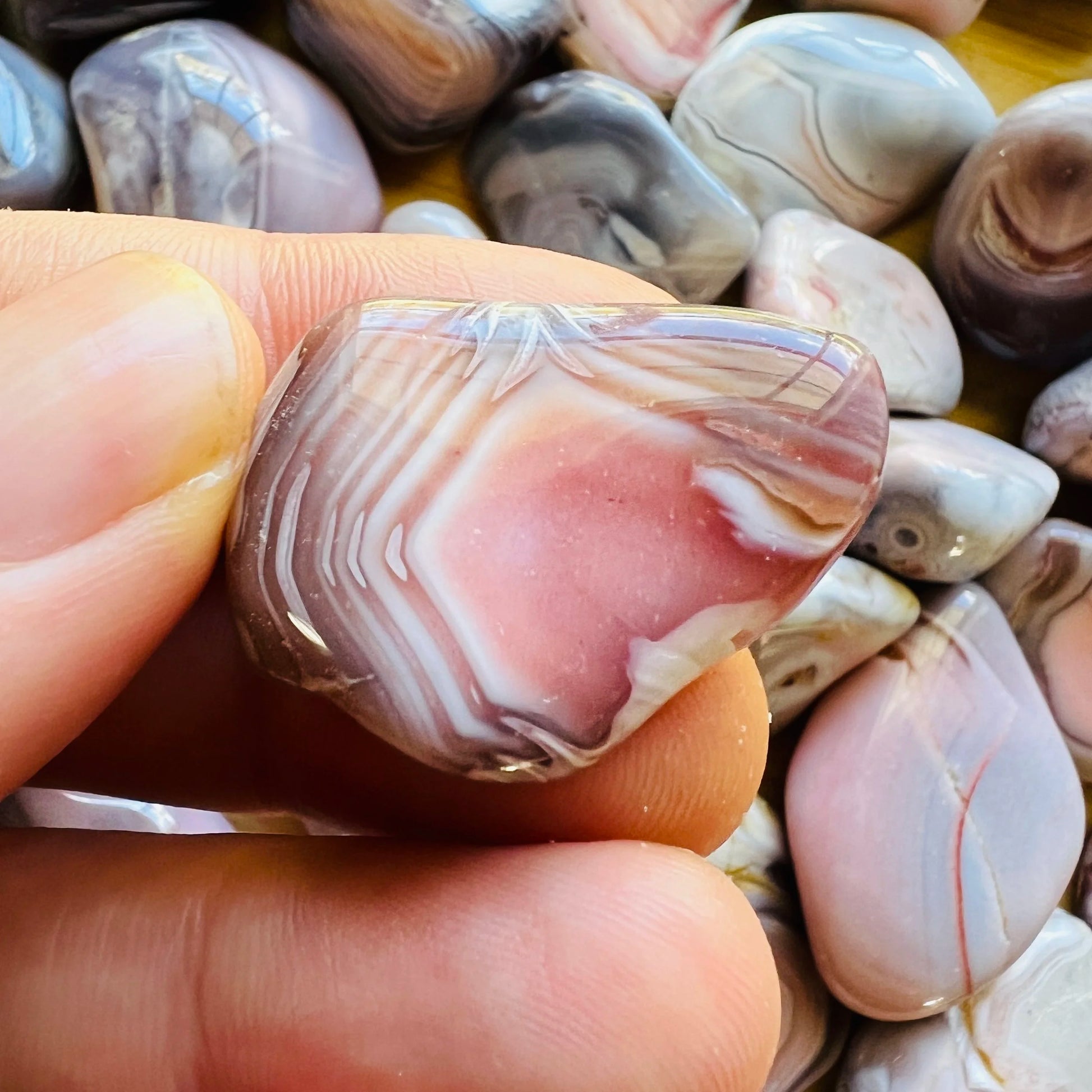 Size comparison with a single Pink Agate tumbled stone sourced from Botswana.