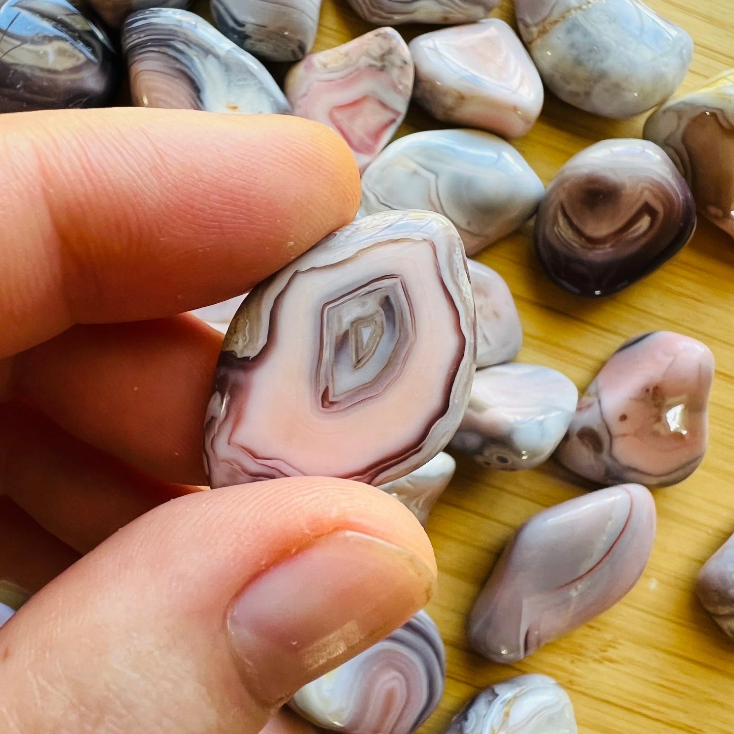 Resting display of Pink Agate tumbled stone, showing natural surface character.