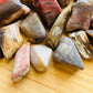 Side-on view of Petrified Wood tumbled stone, hand-selected from Boeny, Madagascar, drawn on for Grounding and Protection.