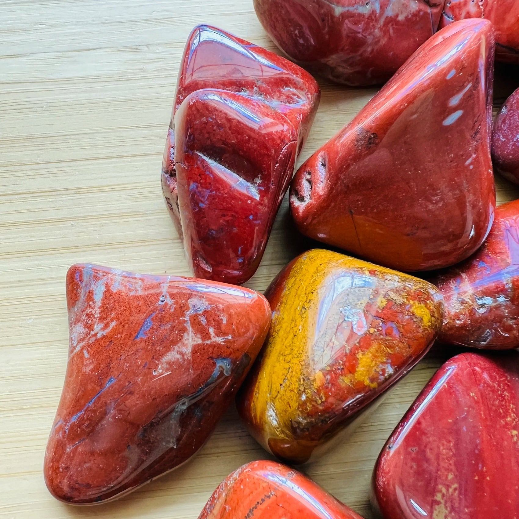 Side angle of Grade AA Red Jasper tumbled stone, sourced from Sofia, Madagascar, showing soft luster.