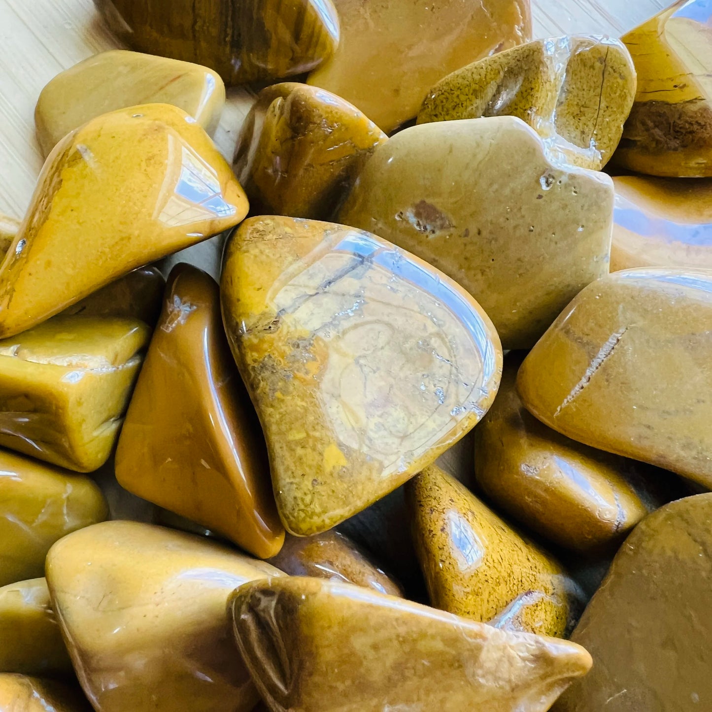 Bottom side of Yellow Jasper tumbled stone, Madagascar-sourced, showing color depth.