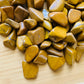 Natural light view of one Yellow Jasper tumbled stone for scale, sourced from Madagascar.