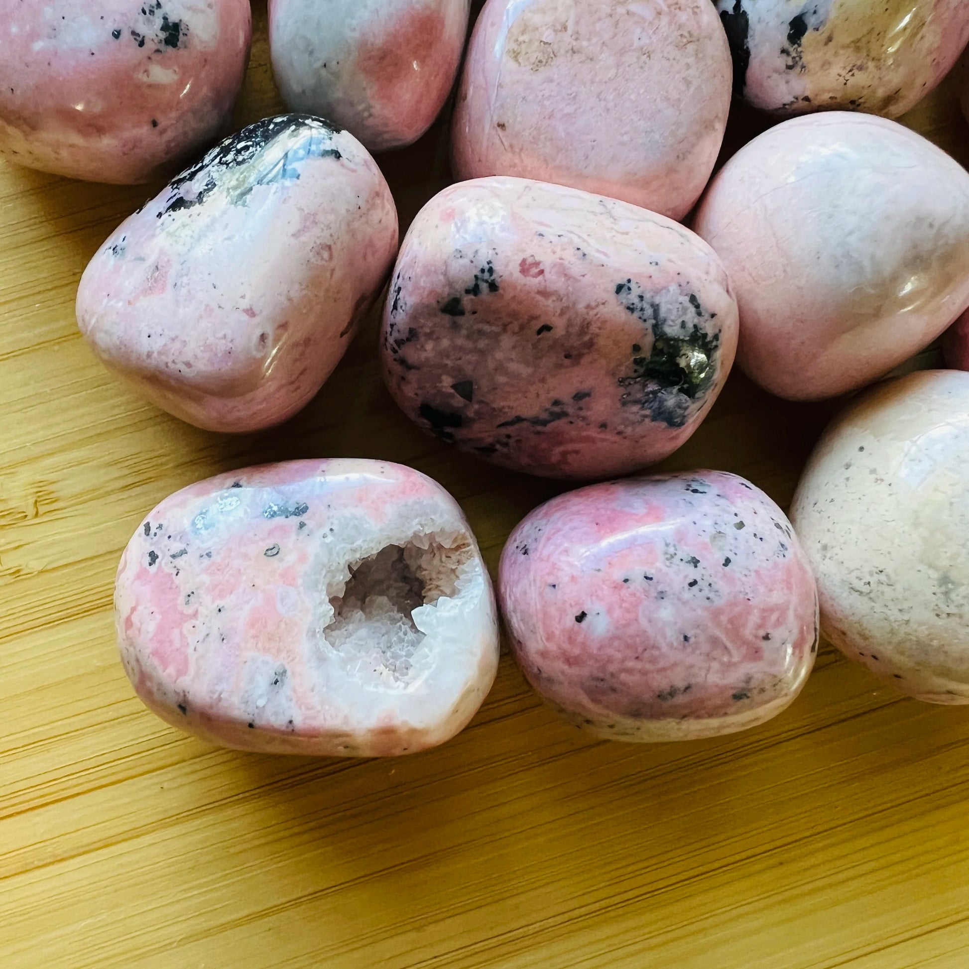 Rear view of Grade AA Rhodonite tumbled stone, showing characteristic color, sourced from Ancash, Peru.
