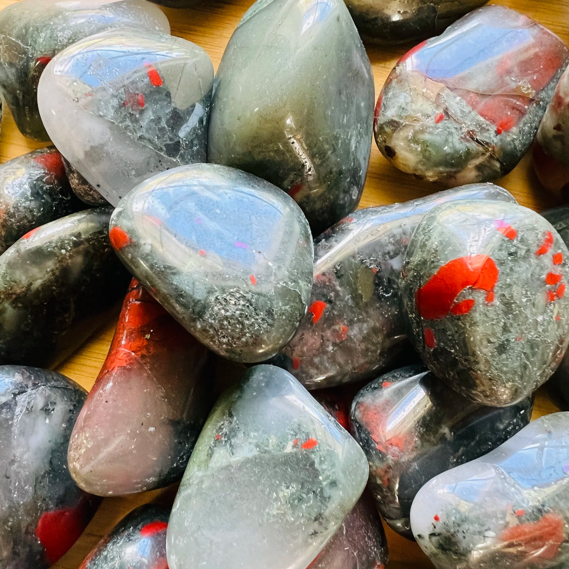 Top-side view of green Bloodstone tumbled stone, showing natural inclusions, often kept for Energy.