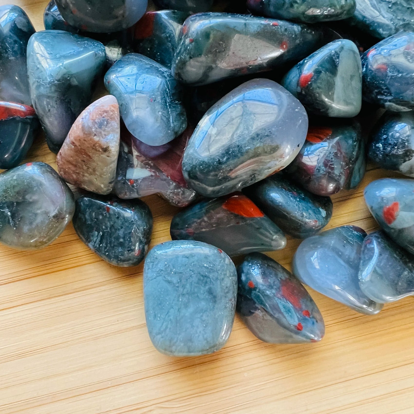 Overhead view of Grade AA Bloodstone tumbled stone, from Eswatini, showing natural variation.