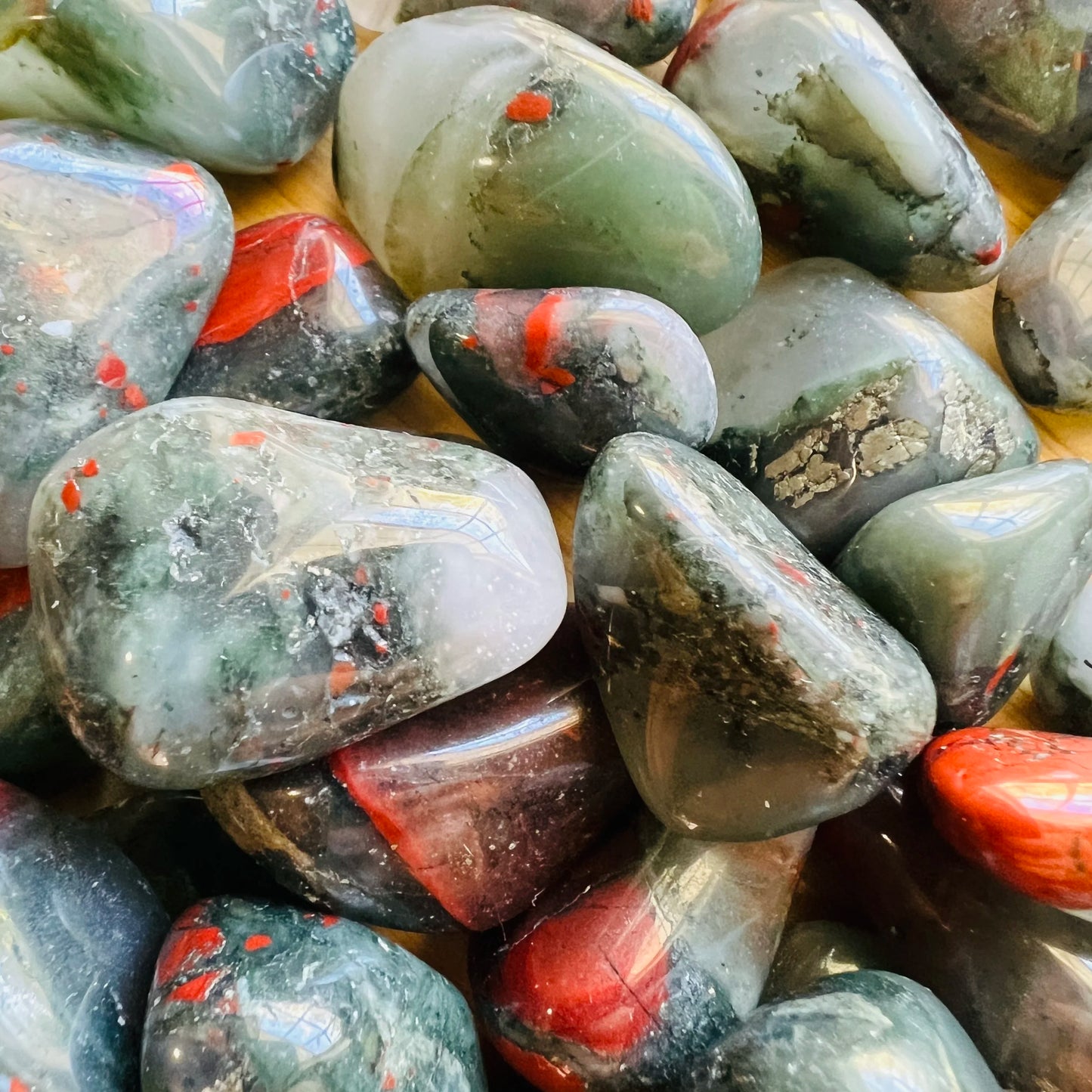 Edge view of Grade AA Bloodstone tumbled stone, showing translucent edges, drawn on for Energy.