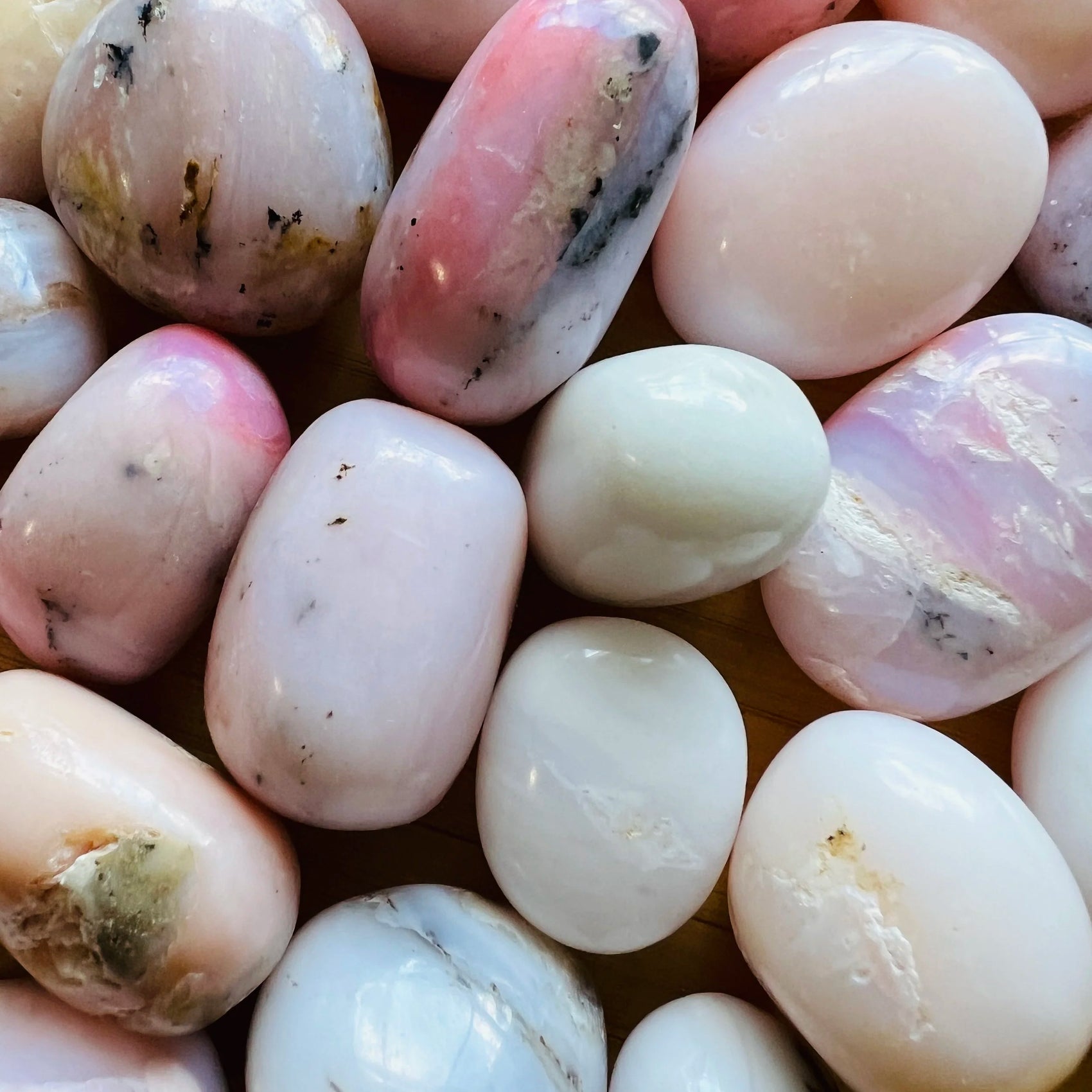 Sideways view of Pink Opal tumbled stone, showing characteristic color, to support Love.