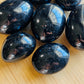 Opposite side of Black Tourmaline palm stone, showing glassy finish, hand-selected from Alaotra-Mangoro, Madagascar.