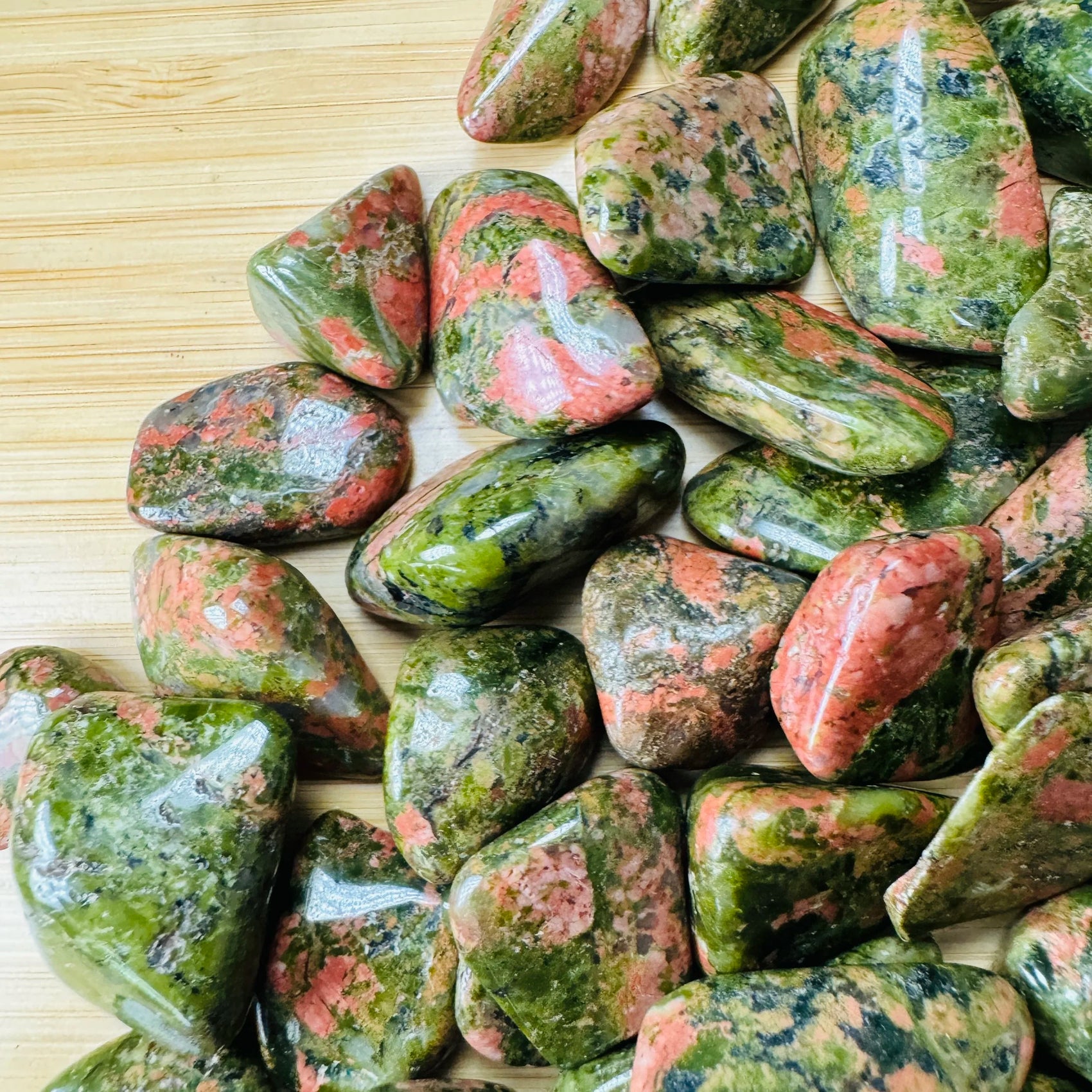 Overhead view of Grade AA green Unakite tumbled stone, often worked with for Emotional Healing.