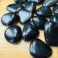 Edge-on view of Grade AA Black Obsidian tumbled stone, sourced from Argentina, showing characteristic finish.
