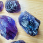 Lifestyle view of a Amethyst raw stone held against natural backdrop, hand-selected from Rio Grande do Sul, Brazil.